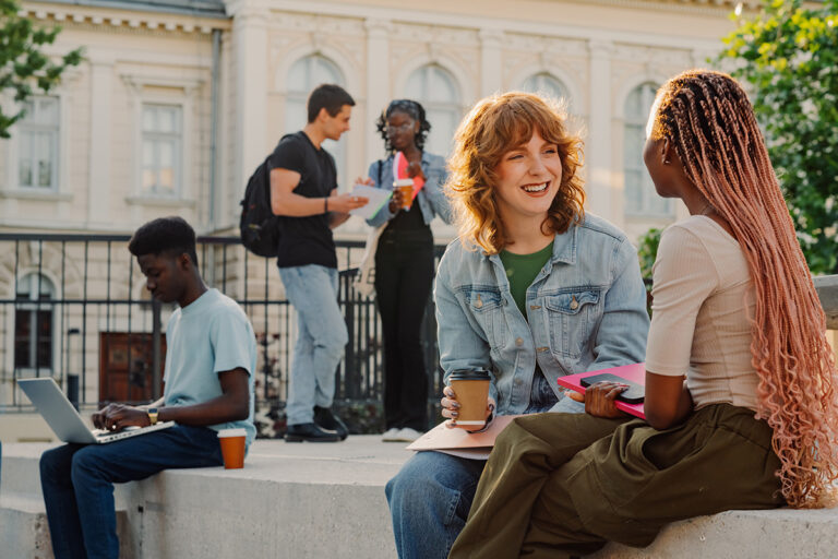 Diverse students on stairs at university campus chatting.